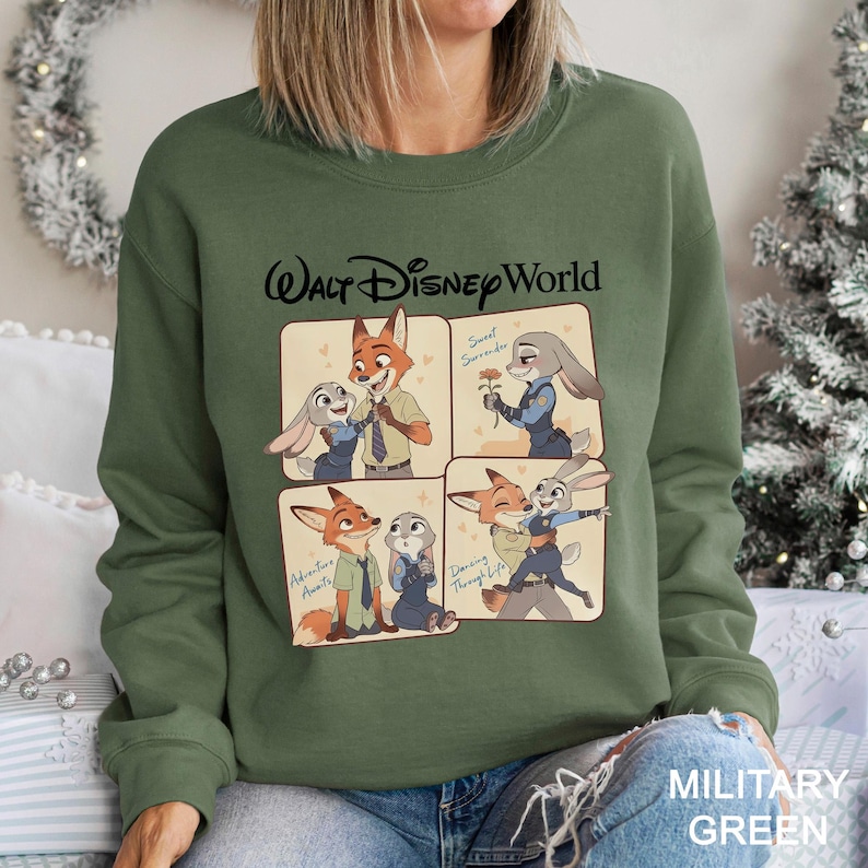 May include: Military green sweatshirt featuring a graphic of Nick Wilde and Judy Hopps from Zootopia, with the text "Walt Disney World." The graphic includes four panels with different scenes of the characters. The sweatshirt is a crew neck.