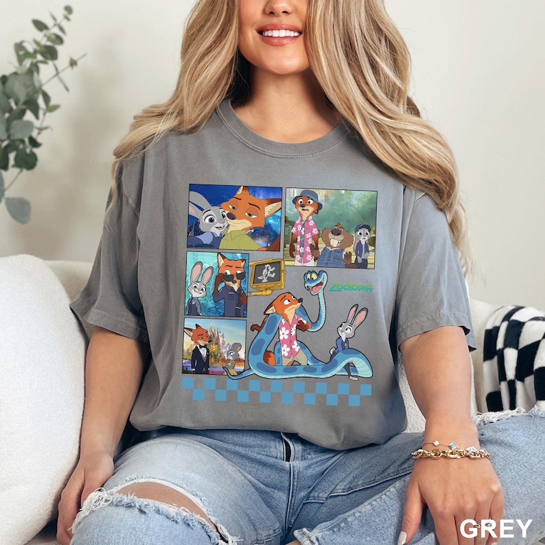 Puede incluir: Camiseta gris con un dise&ntilde;o de c&oacute;mic que presenta personajes de la pel&iacute;cula animada "Zootr&oacute;polis". El dise&ntilde;o incluye im&aacute;genes de un zorro, un conejo y otros personajes. La palabra "Zootr&oacute;polis" est&aacute; impresa en verde.