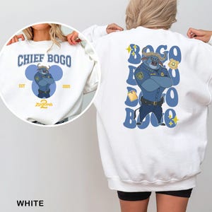 May include: White sweatshirt featuring Chief Bogo from Zootopia. The front has a circular design with the text "CHIEF BOGO" and "EST 2025". The back displays a large illustration of Chief Bogo in a police uniform, with his name in blue letters.