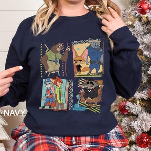 May include: Navy blue sweatshirt with a colourful graphic of animated movie characters. The design features a sloth, fox, bunny, and other characters in a square pattern. The word "NAVY" is printed on the bottom left.