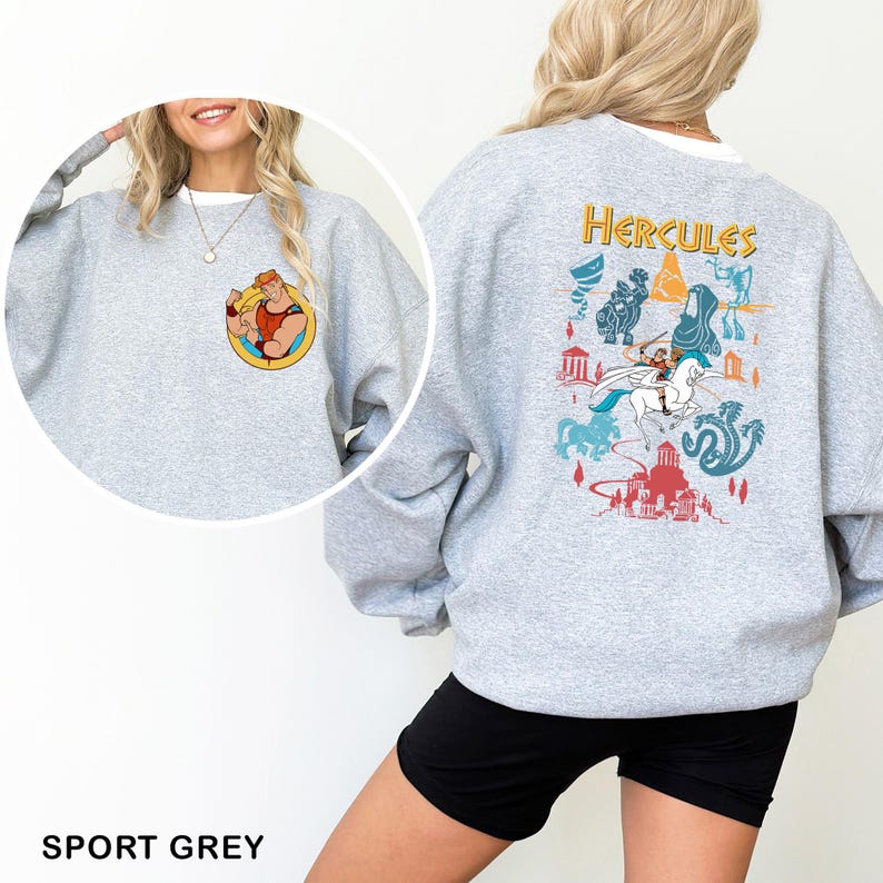 K&ouml;nnte beinhalten: Sportgraues Sweatshirt mit einer Cartoon-Illustration von Herkules auf der Vorder- und R&uuml;ckseite. Die Vorderseite zeigt Herkules beim Posen, w&auml;hrend die R&uuml;ckseite ein farbenfrohes Design mit dem Wort "Hercules" und Szenen aus dem Film zeigt.