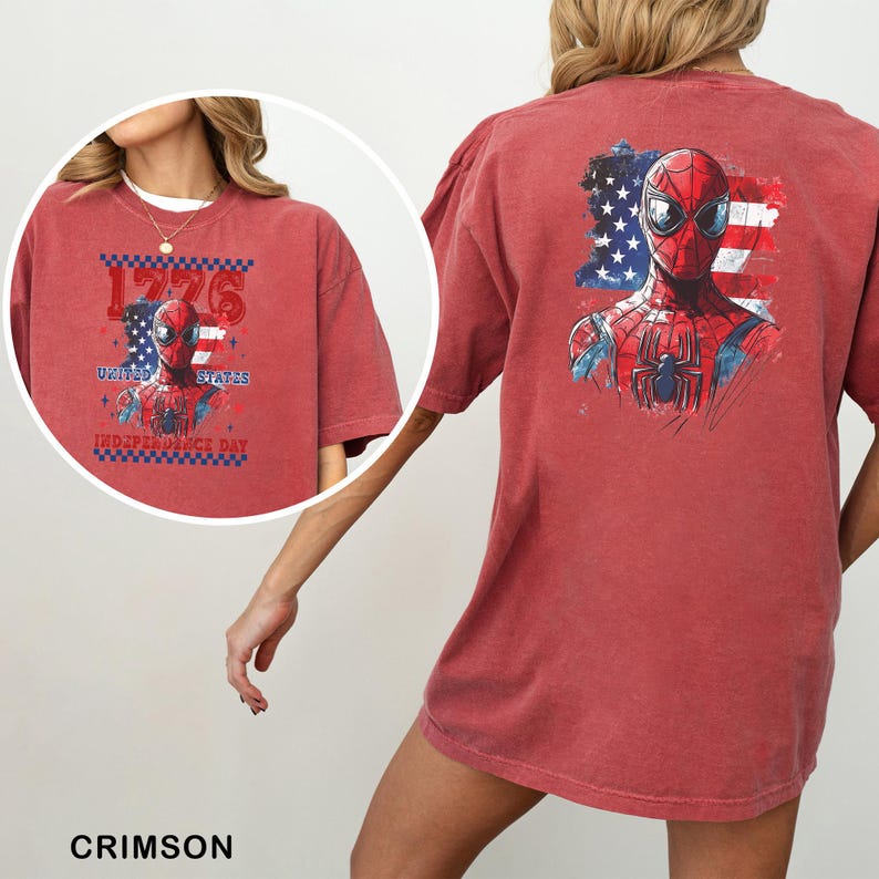 Może przedstawiać: Karmazynowy t-shirt z kr&oacute;tkim rękawem z grafiką Spider-Mana na tle postarzałej amerykańskiej flagi. Z tyłu znajduje się duży nadruk postaci, a z przodu mniejsza wersja z napisem 1776 UNITED STATES INDEPENDENCE DAY.