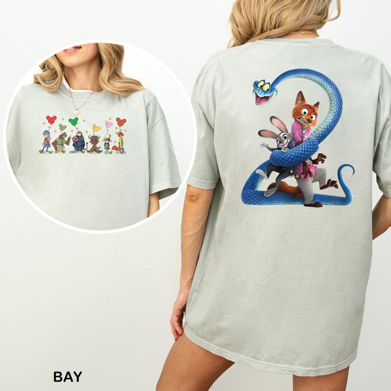 Pu&ograve; includere: T-shirt grigio chiaro con un design a cartoni animati colorato sul davanti e sul retro. Il design anteriore include personaggi dei cartoni animati con palloncini a forma di cuore. Il design posteriore presenta un serpente blu con personaggi dei cartoni animati.