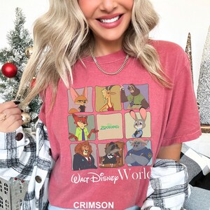May include: Crimson-colored t-shirt featuring a grid of Zootopia characters. The shirt includes the text "Zootopia" and "Walt Disney World" in white. The bottom of the shirt has the word "CRIMSON" in white.