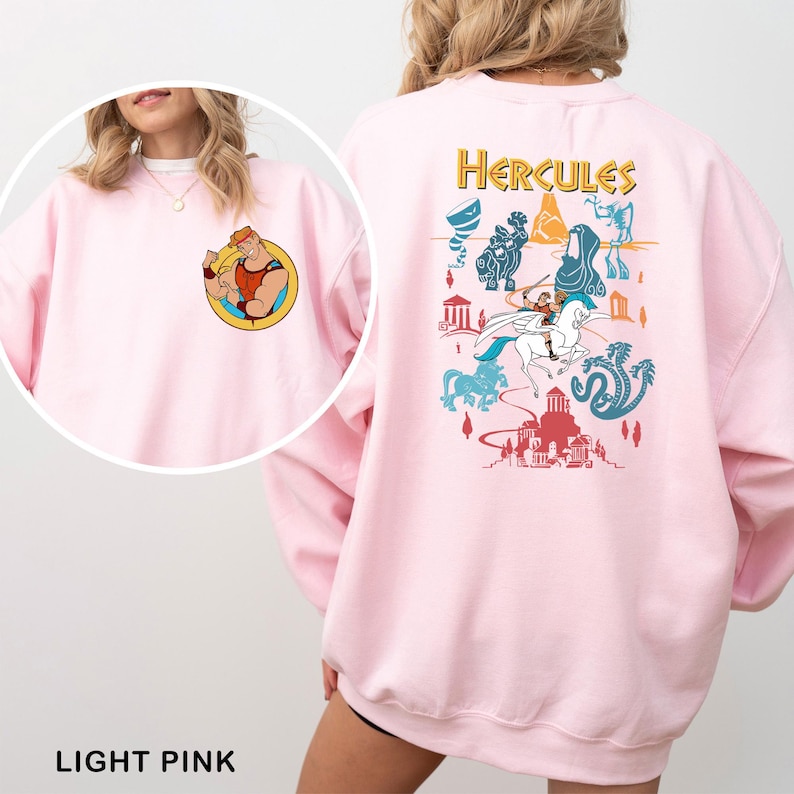 K&ouml;nnte beinhalten: Hellrosa Sweatshirt mit einem Cartoon-Bild von Herkules auf der Vorderseite und einer gr&ouml;&szlig;eren Grafik auf der R&uuml;ckseite. Die R&uuml;ckengrafik enth&auml;lt das Wort "Hercules" in goldfarbenen Buchstaben und verschiedene Cartoon-Charaktere und -Szenen in Blau, Rot und T&uuml;rkis.