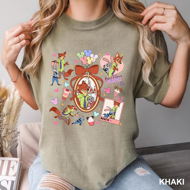 Op de afbeelding: Khaki T-shirt met een kleurrijke afbeelding van cartoon vos- en konijnfiguren. Het ontwerp bevat de tekst "Best Friends Forever" en "Bestie". Het shirt heeft een ronde hals en korte mouwen.