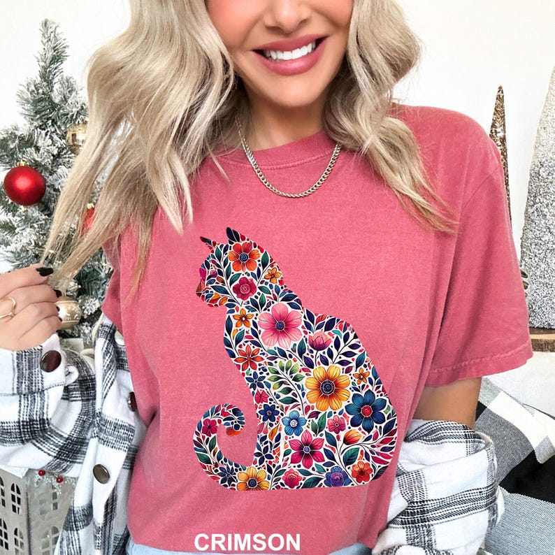May include: Crimson-colored t-shirt featuring a floral cat silhouette. The cat design is filled with colorful flowers in shades of pink, orange, blue, and yellow. The word "CRIMSON" is printed at the bottom of the shirt.