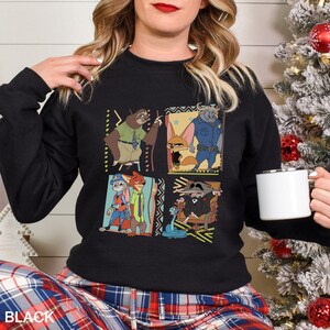 May include: Black crew neck sweatshirt with a colourful graphic of animated film characters. The design features four panels with different characters and decorative borders. The word "BLACK" is printed at the bottom of the sweatshirt.