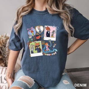 May include: A dark blue t-shirt with a colourful graphic of Zootopia characters. The design includes framed images of the characters, with the word "Zootopia" at the bottom. The shirt is a casual wear item.