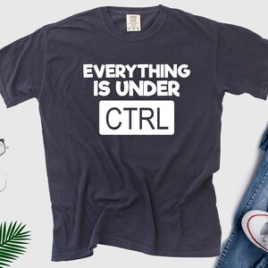 May include: A dark blue t-shirt with white text that reads "Everything is under CTRL".