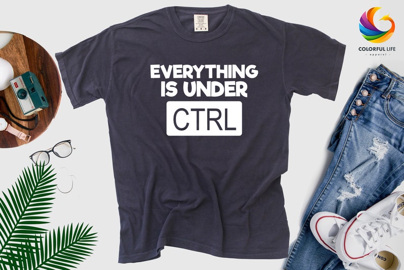 May include: A dark blue t-shirt with white text that reads "Everything is under CTRL".