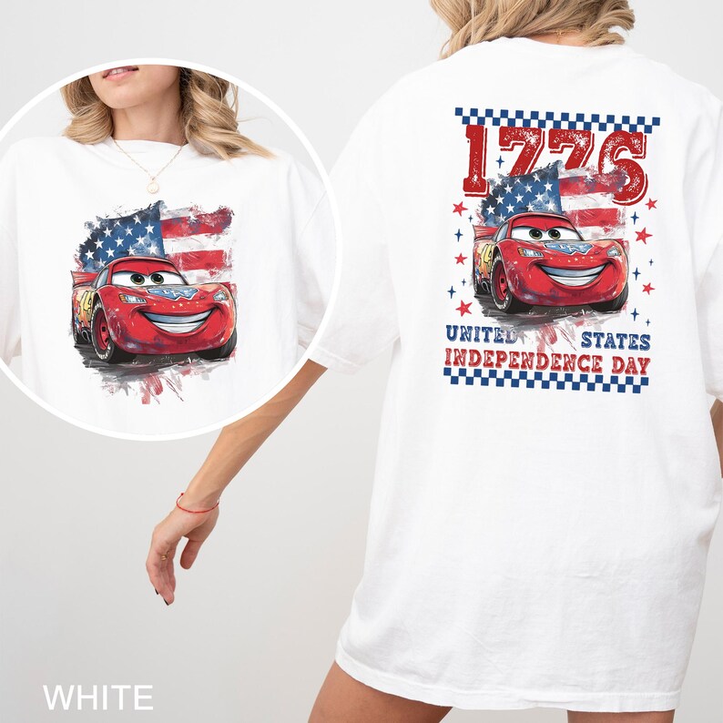 May include: A white t-shirt featuring a graphic of a red race car with a smiling face, positioned in front of a distressed American flag. The design includes the text 1776 and United States Independence Day, accented by red and blue stars.