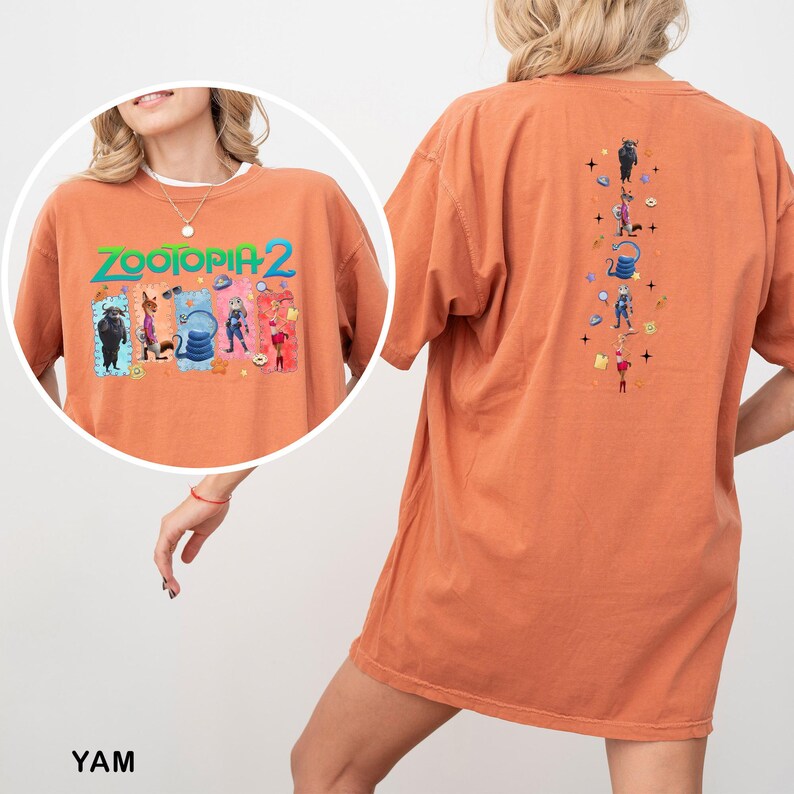 May include: Orange short-sleeved t-shirt featuring the text "ZOOTOPIA 2" with cartoon characters on the front. The back of the shirt has a vertical design with more cartoon characters. The shirt is a comfortable, oversized fit.