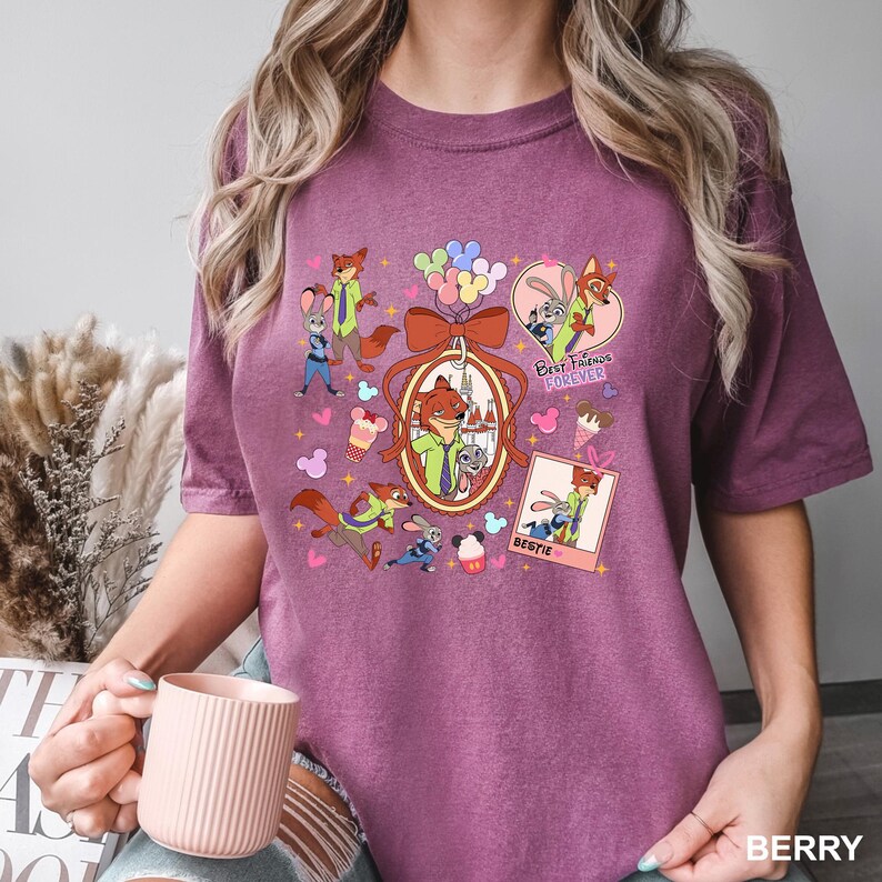 Op de afbeelding: Bessenkleurig T-shirt met stripfiguren uit Zootopia. Het ontwerp bevat Nick Wilde en Judy Hopps, met de tekst "Best Friends Forever" en "Bestie". Het shirt heeft een ronde hals en korte mouwen.