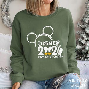 以下が含まれることがあります： 白いミッキーマウスの頭のデザインと「DISNEY 2020 FAMILY VACATION」の文字が入った、ミリタリーグリーンのスウェットシャツ。スウェットシャツはクルーネックです。