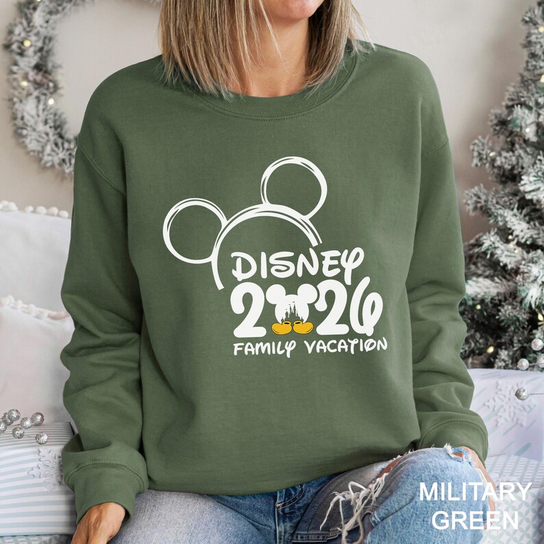 以下が含まれることがあります： 白いミッキーマウスの頭のデザインと「DISNEY 2020 FAMILY VACATION」の文字が入った、ミリタリーグリーンのスウェットシャツ。スウェットシャツはクルーネックです。
