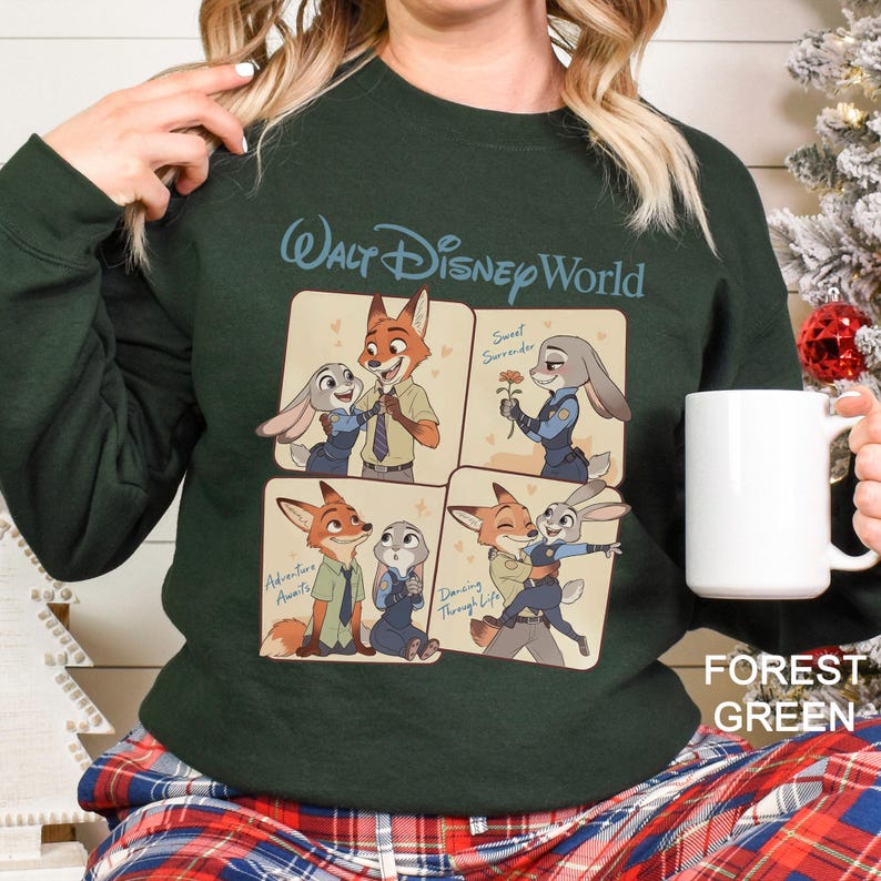 Puede incluir: Sudadera verde bosque con un dise&ntilde;o de Walt Disney World. El dise&ntilde;o incluye cuatro paneles con ilustraciones de Nick Wilde y Judy Hopps de Zootopia. Se incluye el texto "Adventure Awaits", "Sweet Surrender" y "Dancing Through Life".