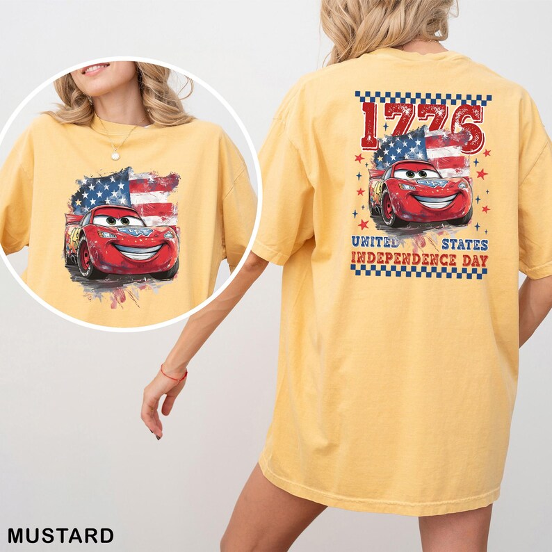 May include: A mustard yellow t-shirt featuring a graphic of a red race car with eyes on the windshield, set against a stylised American flag. The back print includes the text 1776 and UNITED STATES INDEPENDENCE DAY with red stars.