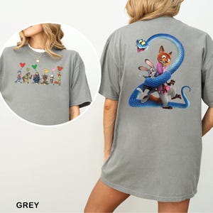 Pu&ograve; includere: T-shirt grigia con un design a cartoni animati sul davanti e sul retro. Il design anteriore mostra personaggi dei cartoni animati con palloncini a forma di cuore. Il design posteriore presenta un serpente blu avvolto attorno a personaggi dei cartoni animati.