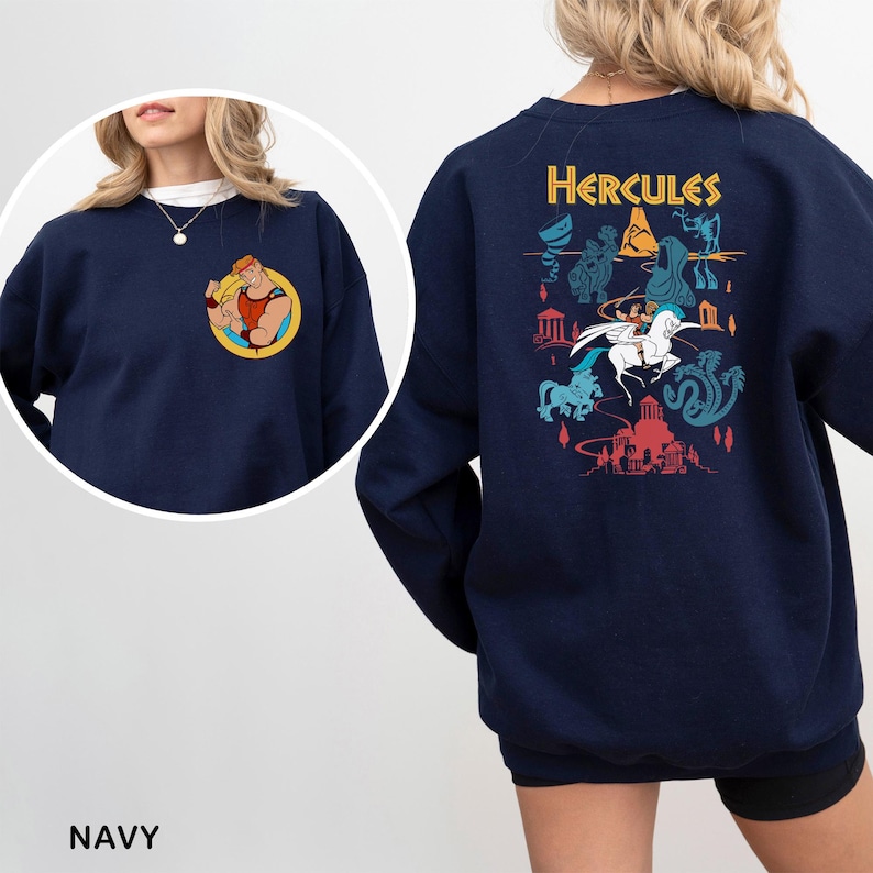 K&ouml;nnte beinhalten: Marineblaues Sweatshirt mit einer farbenfrohen Grafik von Herkules auf dem R&uuml;cken und einem kleineren Bild auf der Vorderseite. Das Design auf der R&uuml;ckseite enth&auml;lt das Wort "Hercules" &uuml;ber einer Szene mit Figuren aus dem Zeichentrickfilm. Die Vorderseite hat ein rundes Bild von Herkules.