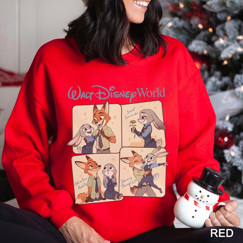 Puede incluir: Una sudadera roja con un dise&ntilde;o de Walt Disney World. El gr&aacute;fico muestra cuatro paneles con im&aacute;genes de dibujos animados de un zorro y un conejo. El texto "Walt Disney World" est&aacute; en azul en la parte superior. La palabra "RED" est&aacute; en blanco en la parte inferior derecha.