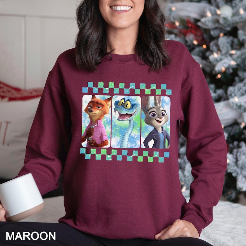 May include: Maroon sweatshirt featuring three cartoon characters in a film strip design. The characters include a fox, a snake, and a rabbit. The sweatshirt has a crew neck and long sleeves. The word "MAROON" is printed at the bottom.