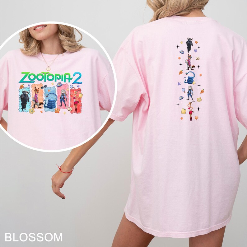 May include: Light pink t-shirt featuring the text "ZOOTOPIA 2" in green and blue, with character illustrations. The back of the shirt has a vertical design with more character illustrations. A casual, comfortable tee.