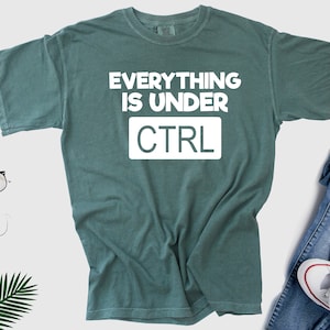 May include: A teal green t-shirt with the text "EVERYTHING IS UNDER CTRL" in white.