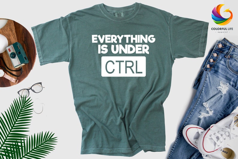 May include: A teal green t-shirt with the text "EVERYTHING IS UNDER CTRL" in white.