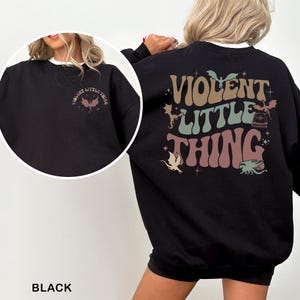 May include: Black sweatshirt with the text "VIOLENT LITTLE THING" in a retro font on the back. The front of the sweatshirt has the same text in a smaller size. The design includes illustrations of bats and dragons.