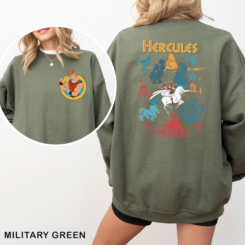 K&ouml;nnte beinhalten: Milit&auml;rgr&uuml;nes Sweatshirt mit einer Cartoon-Grafik von Herkules auf dem R&uuml;cken und einem kleineren Bild auf der Vorderseite. Die R&uuml;ckengrafik enth&auml;lt das Wort "Hercules" und verschiedene Cartoon-Bilder in Blau, Gelb und Rot.