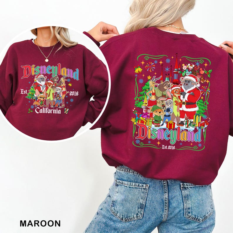 May include: Maroon Disneyland sweatshirt with a colorful graphic on the front and back. The front graphic says "Disneyland" with the text "Est. 2016 California". The back graphic features various cartoon characters and the Disneyland logo.