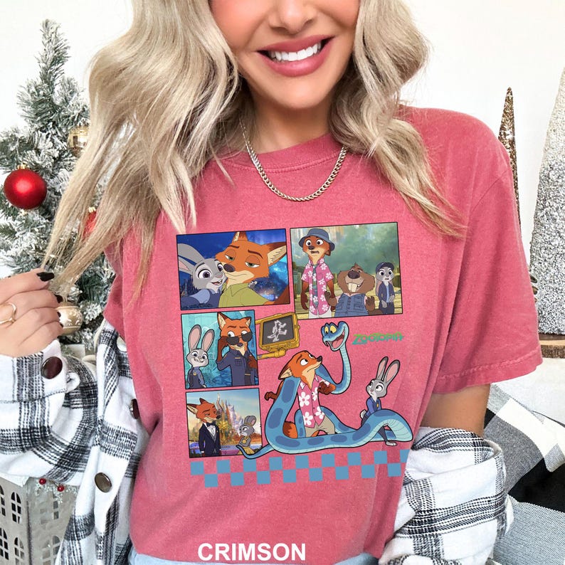 Puede incluir: Camiseta de color carmes&iacute; con un dise&ntilde;o de c&oacute;mic que presenta personajes de dibujos animados, incluyendo un zorro, un conejo y una serpiente. El dise&ntilde;o est&aacute; sobre un patr&oacute;n de cuadros azules y blancos. La palabra "CRIMSON" est&aacute; impresa en la parte inferior.