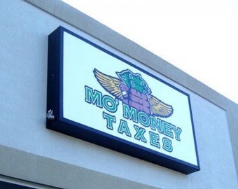 May include: A storefront with a blue and white sign that reads "Mo' Money Taxes". The sign has a cartoon image of a green creature with wings and a money bag.