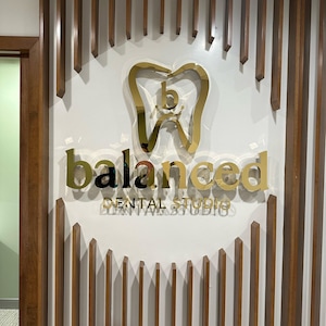 Shiny gold metal dental logo sign.