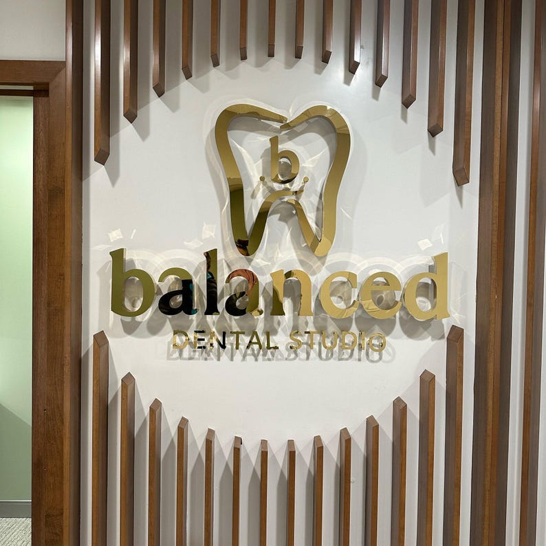 Shiny gold metal dental logo sign.