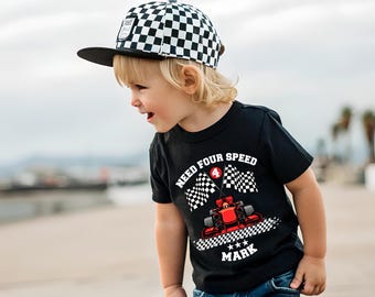 May include: A black t-shirt featuring a red race car graphic, two checkered flags, the text "NEED FOUR SPEED", a red circle with the number "4", and the name "MARK" in white. The shirt is paired with a black and white checkered baseball cap.