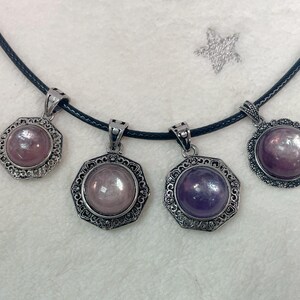 Puede incluir: Cuatro colgantes de plata con piedras preciosas de diferentes colores en un collar de cord&oacute;n negro. Las piedras preciosas son redondas y tienen un acabado met&aacute;lico. Los colgantes son ornamentados y tienen un dise&ntilde;o detallado.