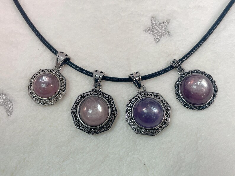 Puede incluir: Cuatro colgantes de plata con piedras preciosas de diferentes colores en un collar de cord&oacute;n negro. Las piedras preciosas son redondas y tienen un acabado met&aacute;lico. Los colgantes son ornamentados y tienen un dise&ntilde;o detallado.
