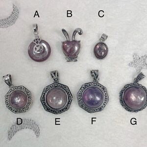 Puede incluir: Ocho colgantes de plata con diferentes dise&ntilde;os y piedras moradas. Los colgantes est&aacute;n etiquetados de la A a la G.