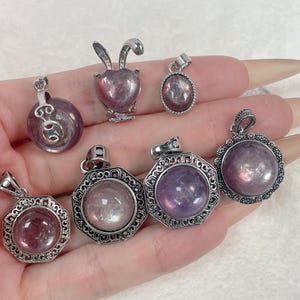 Puede incluir: Siete colgantes de plata con encantos de piedras preciosas p&uacute;rpuras y rosadas. Los colgantes son de varias formas, incluyendo un coraz&oacute;n, un c&iacute;rculo y un oct&oacute;gono.