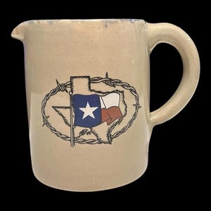 以下が含まれることがあります： ハンドルと注ぎ口が付いたタン色のセラミックピッチャー。ピッチャーは、有刺鉄線の輪郭の中にテキサス州旗のデザインが施されています。旗は白い星が付いた青いフィールドと、白と赤のストライプがあります。