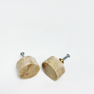 May include: Two beige marble cabinet knobs with a brass screw. The knobs are oval shaped and have a natural stone finish.