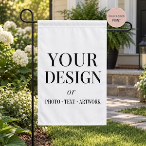 May include: A white rectangular garden flag hanging on a black metal stand. The flag features black text that reads YOUR DESIGN or PHOTO • TEXT • ARTWORK. A circular pink badge in the upper right corner contains the text DOUBLE-SIDED PRINT.