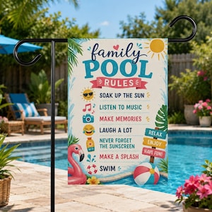 May include: A rectangular garden flag featuring the text family POOL RULES in blue and red. The design includes icons of a sun, music notes, camera, emoji, sunscreen, and lifebuoy, alongside a pink flamingo and beach ball, with colorful signs.