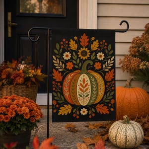 May include: A rectangular garden flag featuring a black background with a central pumpkin illustration decorated with intricate leaf and floral patterns in shades of orange, yellow, green, and cream, surrounded by autumn foliage and berries.