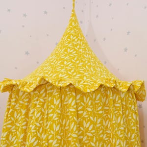 May include: A yellow canopy with a white leaf pattern. The canopy has a ruffled edge and is made of a soft, lightweight fabric.