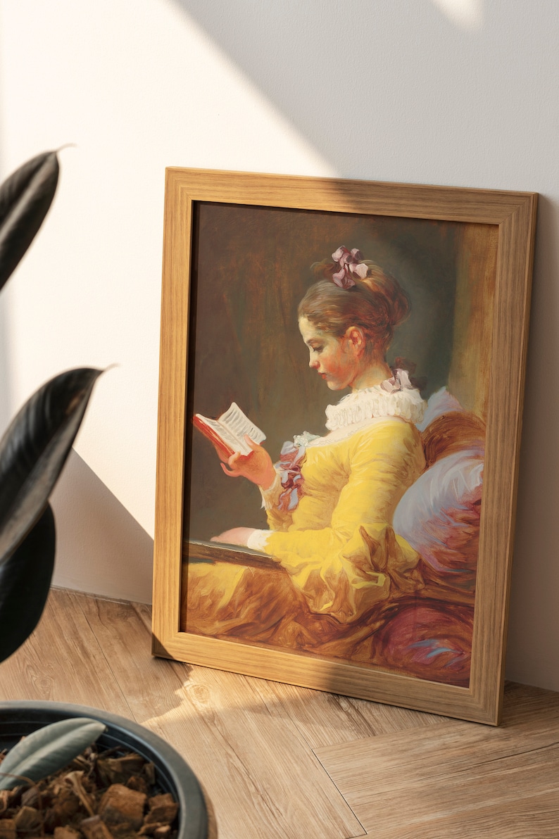 May include: A framed painting of a young woman in a yellow dress reading a book. The painting is set in a room with a soft, warm light. The woman's hair is pulled back and she is wearing a white collar. The painting is framed in a simple wooden frame.