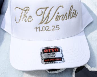May include: White baseball cap with gold embroidery that reads "The Winskis 11.02.25". The cap has a black and white label that reads "OTTO Classic Fit OSFM Mid Profile Maximum Comfort".