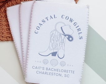 May include: White can cooler with a blue design of cowboy boots and a hat with the text "Coastal Cowgirls" and "Cait's Bachelorette Charleston, SC".
